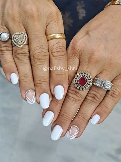A classic white manicure with a stylish accent nail featuring geometric lines and glitter.