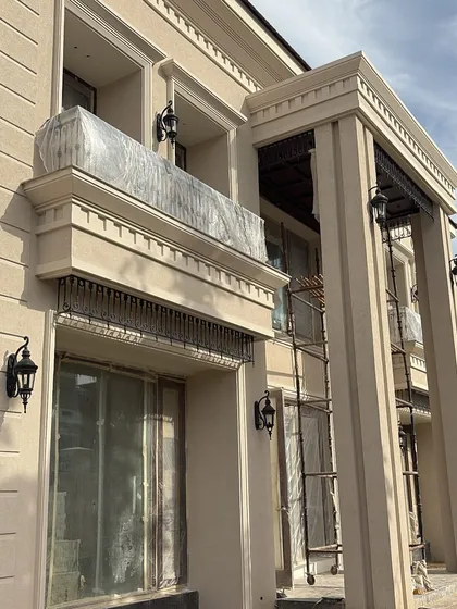 A glimpse of an ongoing project where the classical facade is taking shape. The detailed cornices, columns, and window surrounds are crucial elements that establish the home's architectural character from the outside.