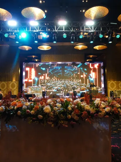 A view from the stage of a gala dinner, showing the impressive technical setup and floral decor. We ensure every element, from the sound system to the flower arrangements, is perfectly executed.