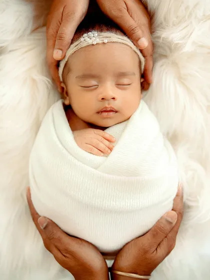 A beautifully swaddled baby girl, held securely in her parents' hands. This classic shot emphasizes how small and precious she is.