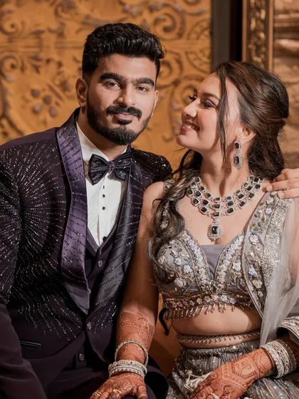 A close-up of the happy couple. The bride's soft glam makeup, with a focus on glowing skin and a beautiful smile, complements her ornate jewelry.