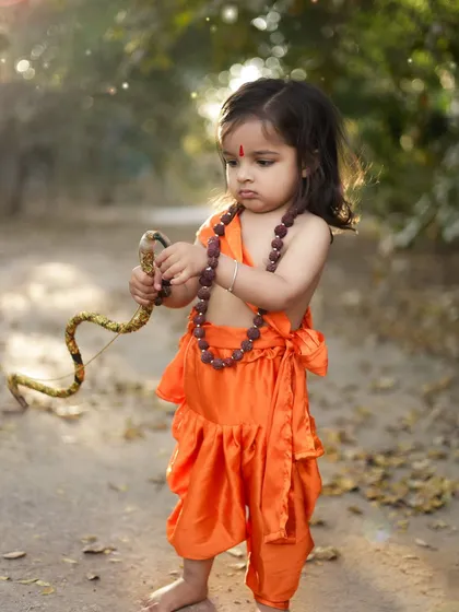 A little girl dressed as Ram, holding a bow and arrow during an outdoor shoot. We are proud to follow our Sanatan dharam and create these photos that teach our children about their heritage.