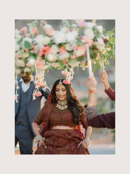 The bride's joyful entry under a floral canopy, her happiness evident in her dance-like steps.