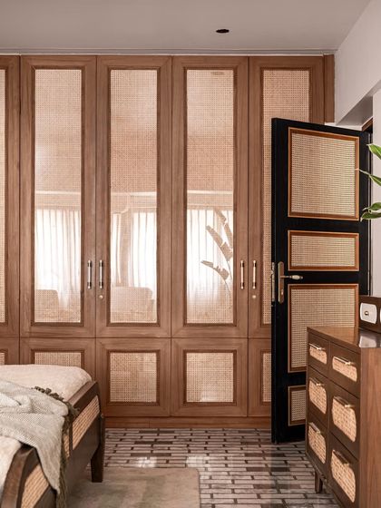 The custom wardrobe in this bedroom is crafted from wood with large cane panels, continuing the natural, textural theme of the space.