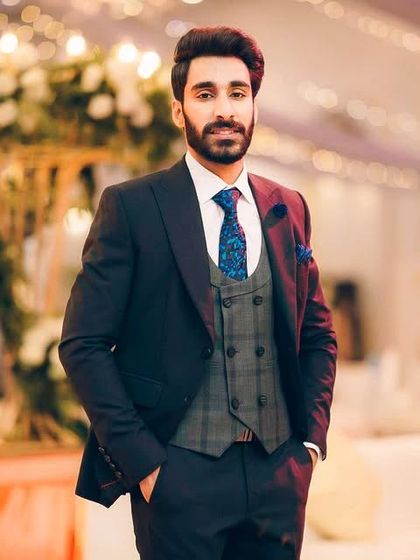 A dashing groom in a three-piece suit. The plaid waistcoat and patterned tie add a touch of personality to this classic reception look.