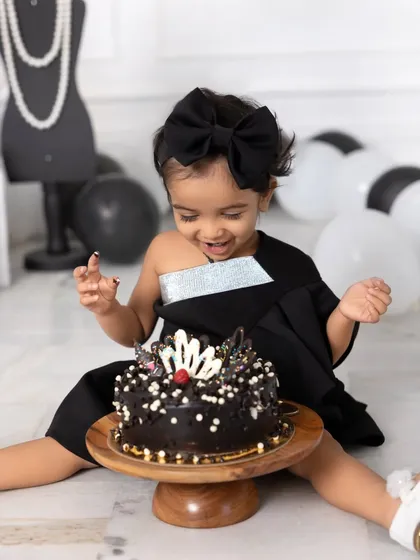 A cake smash with a side of high fashion. This little girl is all smiles as she gets ready to dig into her chic, Chanel-themed birthday cake.