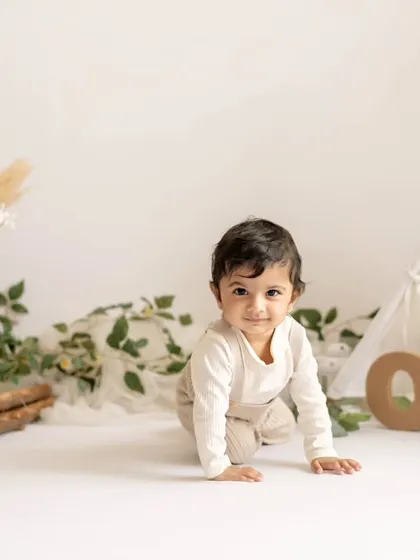 A happy baby crawling in his minimalist boho first birthday setup.