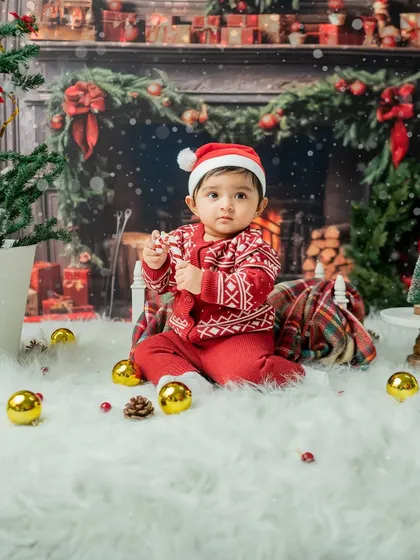 This toddler is enjoying a candy cane in the Christmas setup. The festive sweater and Santa hat make for a classic holiday portrait.