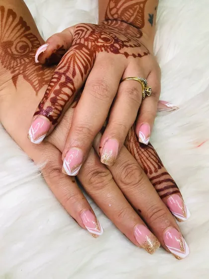 For a more modern bridal style, I created this elegant French manicure with a twist. The design features a V-shaped tip with gold glitter accents, which beautifully complements the artistic henna on her hands.