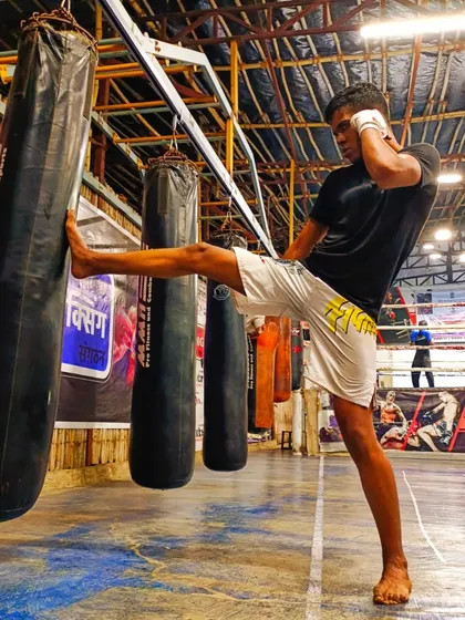 "Punch when you need to punch, kick when you need to kick." A student practices a powerful teep kick on the heavy bag, a crucial tool for controlling distance in a fight.
