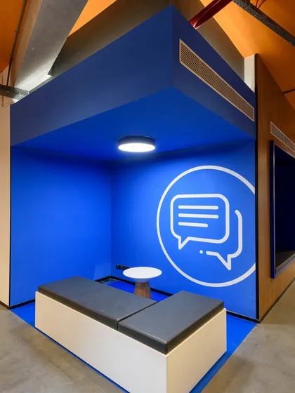 A semi-enclosed huddle space with a bold blue interior and a speech bubble graphic. It's a perfect spot for a quick, informal chat.