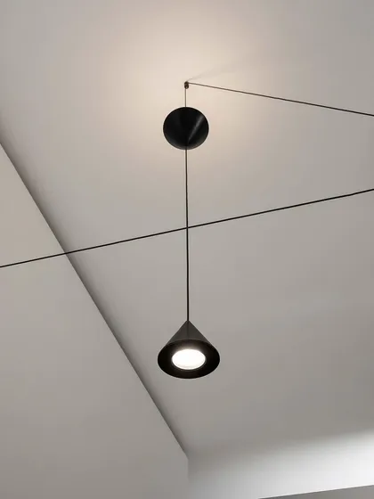 A close-up of a Filomena pendant, showing its simple, elegant cone shape and the clever pulley system that allows for height adjustment.