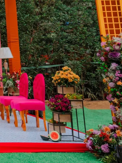 Another angle of the vibrant Mehendi seating area, highlighting the fuchsia chairs and the abundant floral decor that frames the space.