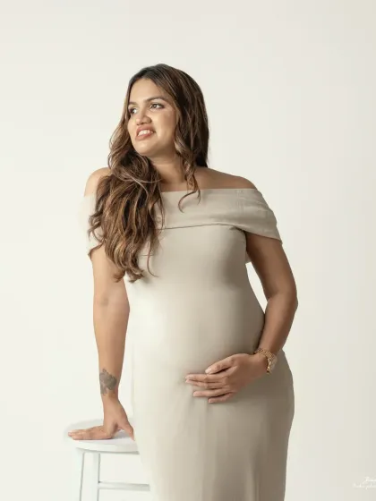A confident and poised solo portrait. The elegant gown and her serene expression create a timeless and graceful image of motherhood.