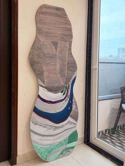 This 6-foot tall artwork on a custom-shaped board was inspired by nature's landscapes. The flowing lines and layered colors mimic riverbeds and mountains, creating an organic and abstract piece for a Mumbai residence.
