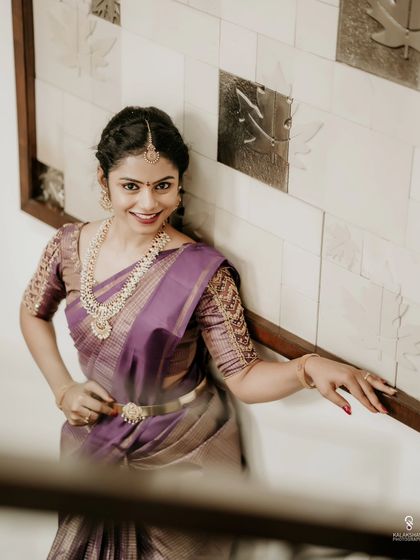 A stylish portrait of a bride in a purple saree, posing on a staircase.