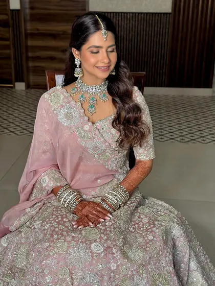 A close-up of the bride, seated and smiling. You can see the details of her soft makeup, with a focus on luminous skin and gently defined eyes.