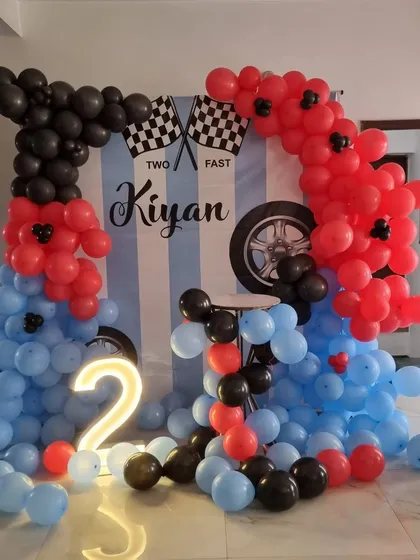 The full setup for the 'Two Fast' racing theme, showing the custom backdrop, light-up number '2', and dynamic balloon arches.