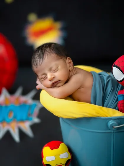 Resting peacefully in his bucket, this newborn is joined by his superhero friends Spider-Man and Iron Man in this fun, custom setup.