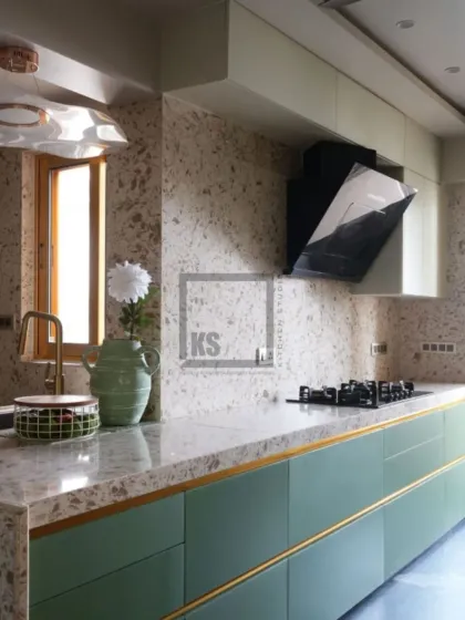 We love blending different materials to create a unique feel. This kitchen features a beautiful combination of muted green matte glass cabinets with elegant gold handles, paired with a durable terrazzo countertop and backsplash for a look that is both modern and timeless.