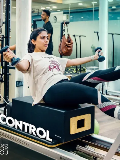 Achieve control over your body and breath. This client is using dumbbells on the reformer box to add an upper body strength challenge to her core work.