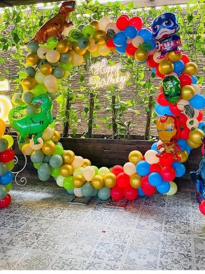 A mixed-theme party combining dinosaurs and superheroes. This outdoor balloon ring is decorated with colorful balloons and foil balloons of dinosaurs and Avengers characters.