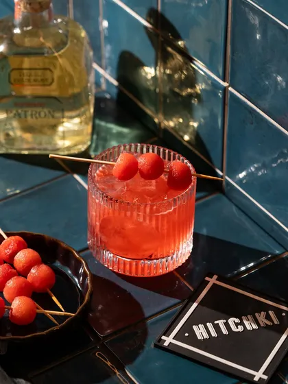 A vibrant watermelon tequila cocktail against a bold, blue-tiled background. I use color theory to make my drink photography pop and match the brand's aesthetic.