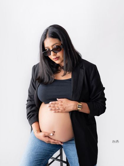 A modern and chic maternity look with a blazer, crop top, and sunglasses. Your maternity shoot should reflect your personal style.