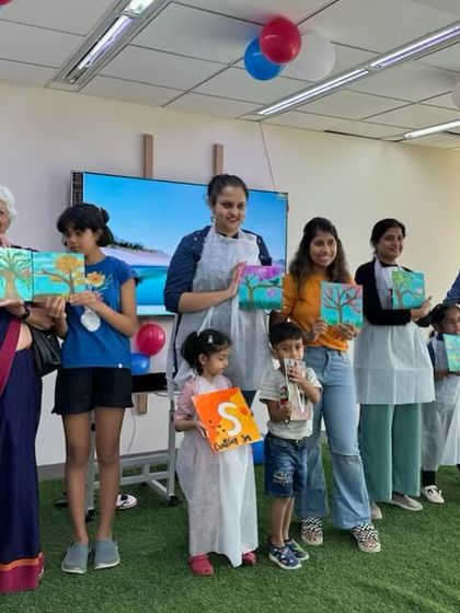 A group of participants, from young children to grandmothers, showing off their finished tree paintings. Our workshops are truly for all ages, encouraging intergenerational bonding.
