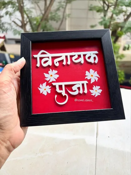 A clear shot of the 'Vinayak Puja' nameplate, showing the 3D effect of the lettering against the vibrant red background.