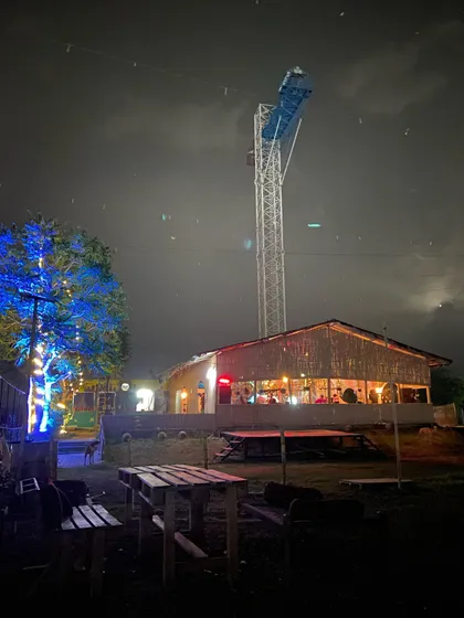 The vibe at our venue after dark. This shot captures our cozy cafe area and the towering bungee jumping platform lit up against the night sky, showcasing the blend of chill hangout spots and high-adrenaline adventure we offer.