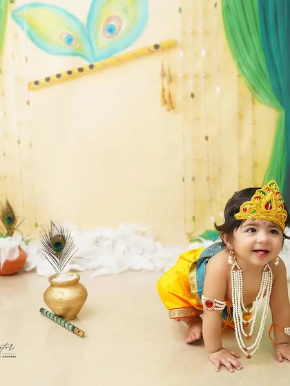 On the move! This little Krishna is crawling towards his next adventure, with a pot of butter and a peacock feather nearby.