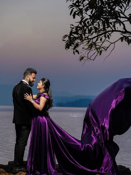 A romantic embrace as the sun sets over the water. The deep purple trail gown adds a sense of luxury and drama to this beautiful pre-wedding moment.
