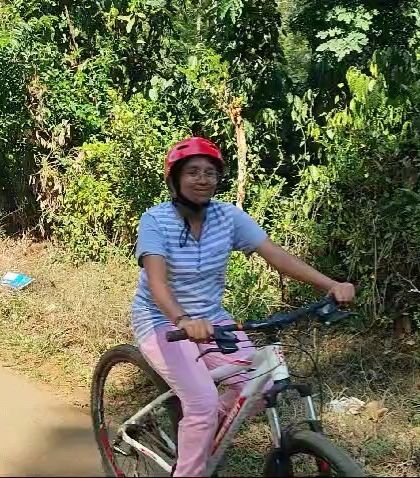 A smiling camper enjoys a leisurely bike ride on a quiet path during the nature awareness camp.
