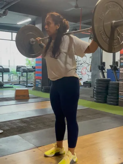 A female client holding a stable overhead position after a drop snatch, demonstrating good shoulder mobility and core control.