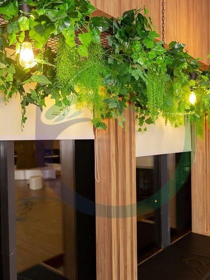 In this office breakout area, we installed artificial vines along the wooden pillars and ceiling. This simple addition brings a sense of warmth and nature to the modern design, making it a more inviting place to take a break.