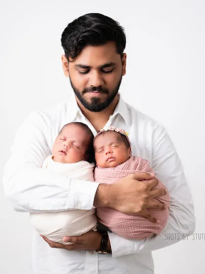 A proud father holding his twin newborns. Double the love, double the joy.