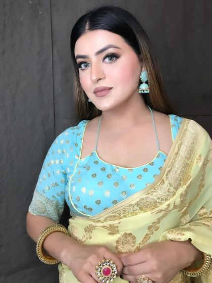 A close-up of a soft and pretty party look. The focus is on a flawless base, a neutral lip, and defined eyes, letting the beautiful saree and jewelry shine.