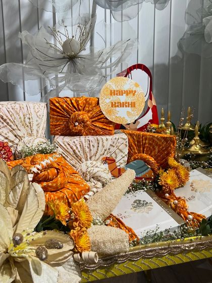 A beautiful Rakhi platter featuring gifts wrapped in traditional orange bandhani fabric. This is a perfect blend of modern presentation and traditional textiles.