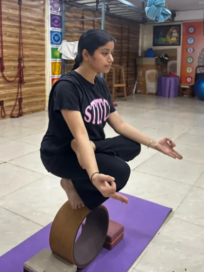 A student holds a toe-stand balance on a yoga wheel, showcasing the core strength and concentration developed in our classes.