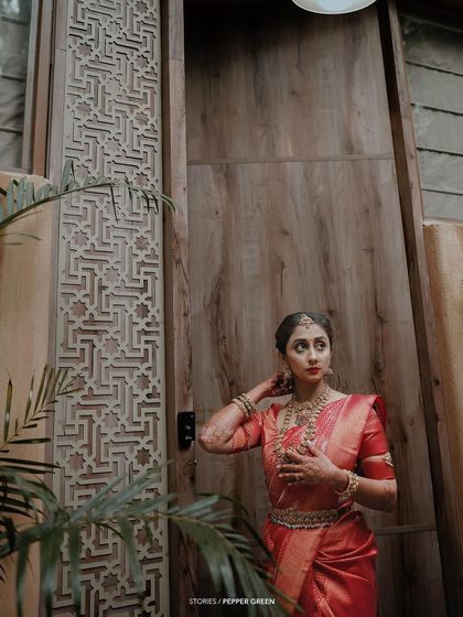 A portrait of the bride, Bhagya, looking thoughtful and elegant. The intricate wooden door behind her adds a touch of traditional architectural beauty.
