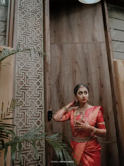 An elegant portrait of the bride, her pose thoughtful, set against a beautifully carved wooden door.