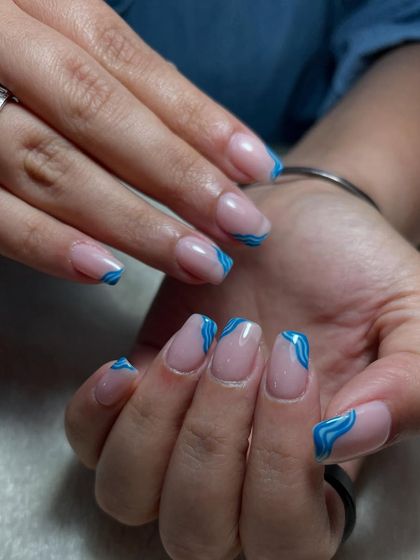 Subtle yet stylish. These blue swirl tips on a nude base bring a modern, abstract, and effortless vibe to your nails.