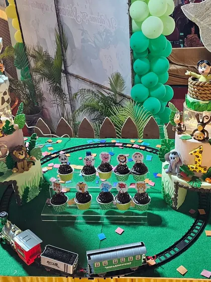 The full dessert spread with the twin jungle cakes and matching animal-themed cupcakes.