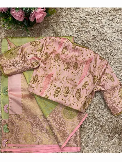 A full view of the pink and green saree set, showing the blouse with its embroidered parrot motifs and the elegant drape of the silk saree.