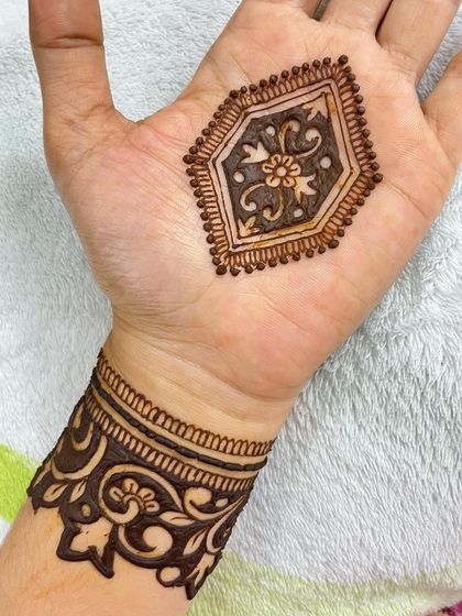 A simple yet bold design with a geometric floral motif on the palm and a thick, dark cuff on the wrist.