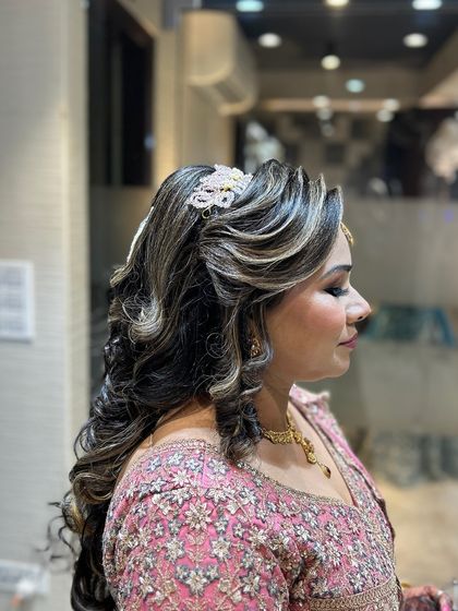 A side view of a glamorous open hairstyle with highlighted curls and a sparkling accessory.
