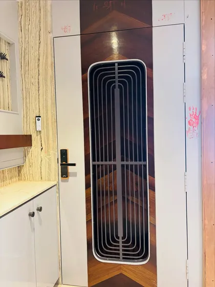 A stylish entrance featuring a safety door with a combination of white and dark wood veneer in a chevron pattern.