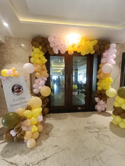 This is an entrance decoration we designed for a baby's naming ceremony. A custom welcome sign and an organic balloon arch in earthy tones of brown, yellow, and pink greet guests as they arrive at the venue.