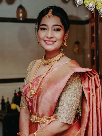 A bride looking elegant in a peach-toned Kanchipuram saree. Her custom blouse features delicate paisley embroidery on the sleeves, adding a touch of classic charm.